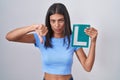 Brunette young woman holding l sign for new driver with angry face, negative sign showing dislike with thumbs down, rejection Royalty Free Stock Photo