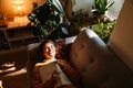 Brunette young woman reading book while resting on couch Royalty Free Stock Photo