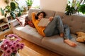 Brunette young woman reading book while resting on couch Royalty Free Stock Photo