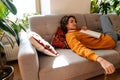 Brunette young woman reading book while resting on couch Royalty Free Stock Photo