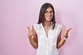 Brunette young woman standing over pink background wearing glasses success sign doing positive gesture with hand, thumbs up Royalty Free Stock Photo