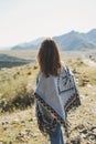 Brunette young woman traveler in poncho from back on road, trip to the mountains, Altai