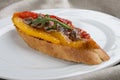 Bruschetta with anchovies and grilled pepper on a white plate, on a textile background