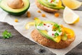 Bruschetta with avocado, yellow pepper, grains of corn, parsley and chili pepper on a light wooden background.