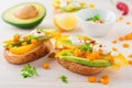 Bruschetta with avocado, yellow pepper, grains of corn, parsley and chili pepper on a light wooden background.