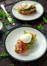 Bruschetta with cream cheese, wilde rucola, parma ham and poached egg served on white plate. Royalty Free Stock Photo