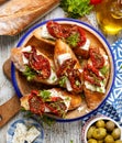 Bruschetta with feta cheese, dried tomatoes, olive oil and fresh aromatic herbs, on a plate on a wooden table, top view. Royalty Free Stock Photo