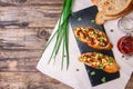 Bruschetta with feta cheese, dried tomatoes, olive oil and fresh microgreen herbs, on a stone plate on a wooden table.