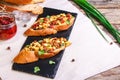 Bruschetta with feta cheese, dried tomatoes, olive oil and fresh microgreen herbs, on a stone plate on a wooden table. Royalty Free Stock Photo