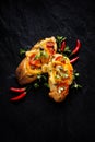 Bruschetta, grilled baguette with addition of tomatoes, cheese and herbs on a black background, top view.