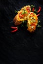 Bruschetta, grilled baguette with addition of tomatoes, cheese and herbs on a black background, top view.