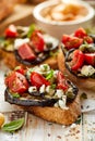 Bruschetta with grilled eggplant, cherry tomatoes, feta cheese, capers and fresh aromatic herbs on a wooden table. Delicious Medit Royalty Free Stock Photo