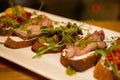 Bruschetta with ham and greens on a white plate. Appetizer in italian restaurant, mediterranean cuisine Royalty Free Stock Photo