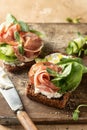 Bruschetta with ham or prosciutto, cream cheese, cucumber, spinach and microgreens. Tasty sandwich or toasted bread on Royalty Free Stock Photo