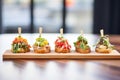 bruschetta lineup on a long wooden paddle, different colors popping