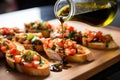 bruschetta platter with dripping olive oil, mid-pour