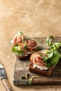 Bruschetta with prosciutto, cream cheese, cucumber, spinach and microgreens. Tasty sandwich or toasted bread on wooden Royalty Free Stock Photo