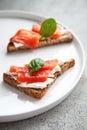 Bruschetta with red fish and cream cheese with black bread on white plate Royalty Free Stock Photo