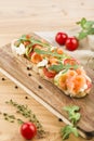 Bruschetta with salmon, arugula and cherry tomatoes on a board on a light wooden background Royalty Free Stock Photo