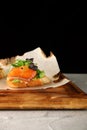 Bruschetta with salmon closeup. tapas with salmon on guacamole and topped microgreen on wooden board and black background