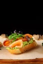 Bruschetta with salmon closeup. tapas with salmon on guacamole and topped microgreen on wooden board and black background