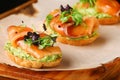 Bruschetta with salmon closeup. tapas with salmon on guacamole and topped microgreen on wooden board and black background