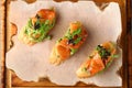 Bruschetta with salmon on wood top view. Smoked salmon toast with guacamole and microgreen