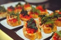 Bruschetta with shrimps, basil, pesto and mozzarella sauce and tomato on a white plate on a wooden background. Italian restaurant Royalty Free Stock Photo