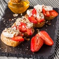 Bruschetta with strawberries, blue cheese, walnut and honey on stoyn plate