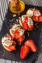 Bruschetta with strawberries, blue cheese, walnut and honey on stoyn plate
