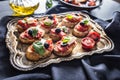 Bruschetta toast with mozzarella tomatoes olives and basil.