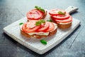 Bruschetta, toast with soft cheese, basil and tomatoes on a white wooden board. Italian healthy snack, food. Royalty Free Stock Photo