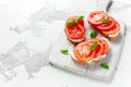 Bruschetta, toast with soft cheese, basil and tomatoes on a white wooden board. Italian healthy snack, food. Royalty Free Stock Photo