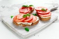 Bruschetta, toast with soft cheese, basil and tomatoes on a white wooden board. Italian healthy snack, food.