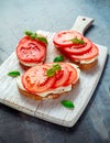 Bruschetta, toast with soft cheese, basil and tomatoes on a white wooden board. Italian healthy snack, food. Royalty Free Stock Photo