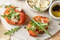 Bruschetta with tomatoes, arugula, olive oil and cheese on plate on textured background close up. Fresh italian toasts