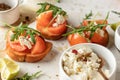 Bruschetta with tomatoes, arugula, olive oil and cheese on white tray on textured background. Fresh italian toasts