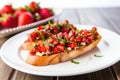 bruschetta topped with fresh strawberries on a white plate