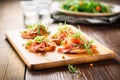 bruschettas with prosciutto and arugula on wooden board