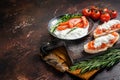 Bruschettas with stracciatella cheese, chopped cherry tomatoes and rosemary. Dark background. Top view. Copy space Royalty Free Stock Photo