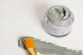 A brush for applying face masks, a jar of cosmetic blue clay and a smear of clay on a textured light background copy space Royalty Free Stock Photo