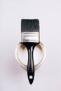 Brush with black handle on open can of white paint on grey background. Royalty Free Stock Photo