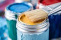 Brush close up on vibrant paint cans, artistic tools and colors