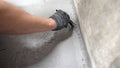 Brush with gray primer. A man paints the concrete floor in his bathroom with a gray brush. Waterproofing the floor in