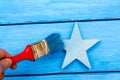 Brush in hand colors blue wooden star on a blue background Royalty Free Stock Photo