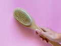 Brush with a handle for dry anti-cellulite massage or brushing in the hand of a girl on blue background.  Beauty concept Royalty Free Stock Photo