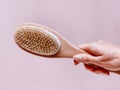 Brush with a handle for dry anti-cellulite massage or brushing in the hand of a girl in soft pink colors.  Beauty concept Royalty Free Stock Photo