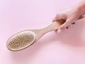 Brush with a handle for dry anti-cellulite massage or brushing in the hand of a girl in soft pink colors.  Beauty concept Royalty Free Stock Photo