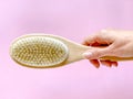 Brush with a handle for dry anti-cellulite massage or brushing in the hand of a girl in soft pink colors.  Beauty concept Royalty Free Stock Photo