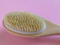 Brush with a handle for dry anti-cellulite massage or brushing in the hand of a girl in soft pink colors.  Beauty concept Royalty Free Stock Photo